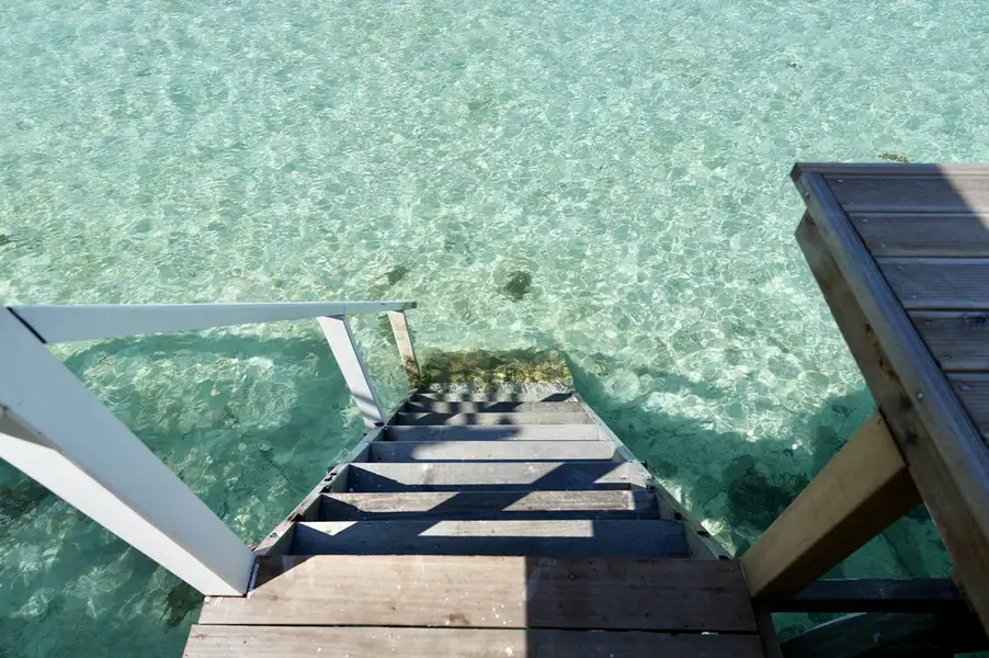 Private sunlit balcony featuring direct wooden stairs to the sea at F-Lina Water Villa Resort. An over water haven offering barefoot luxury and snorkeling access to the Celebes Sea.