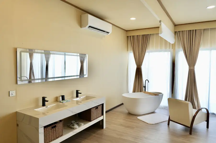 A modern open-concept bathroom at F-Lina Water Villa Resort featuring a freestanding bathtub, dual marble-style vanity with black faucets, and A/C.